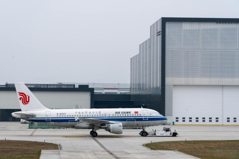 Air China plane parked at an airport hangar on a cloudy day, ready for takeoff.