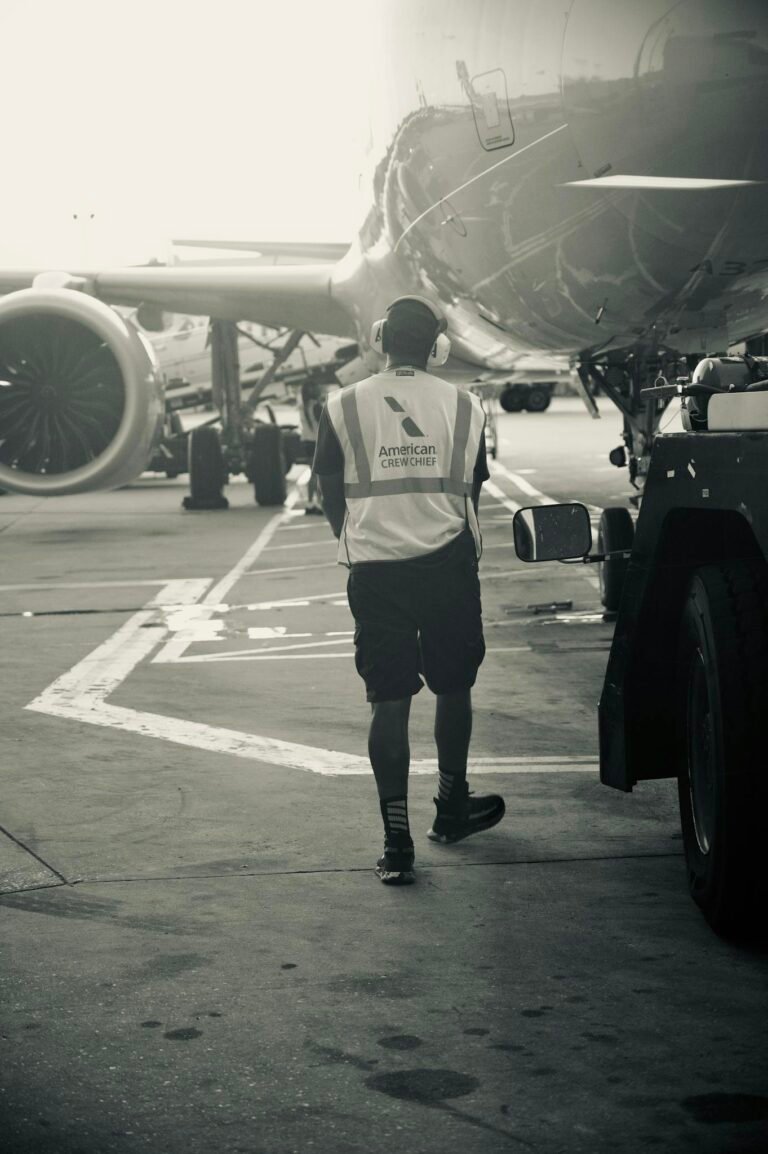 Ground crew member in safety vest walks near airplane at airport terminal