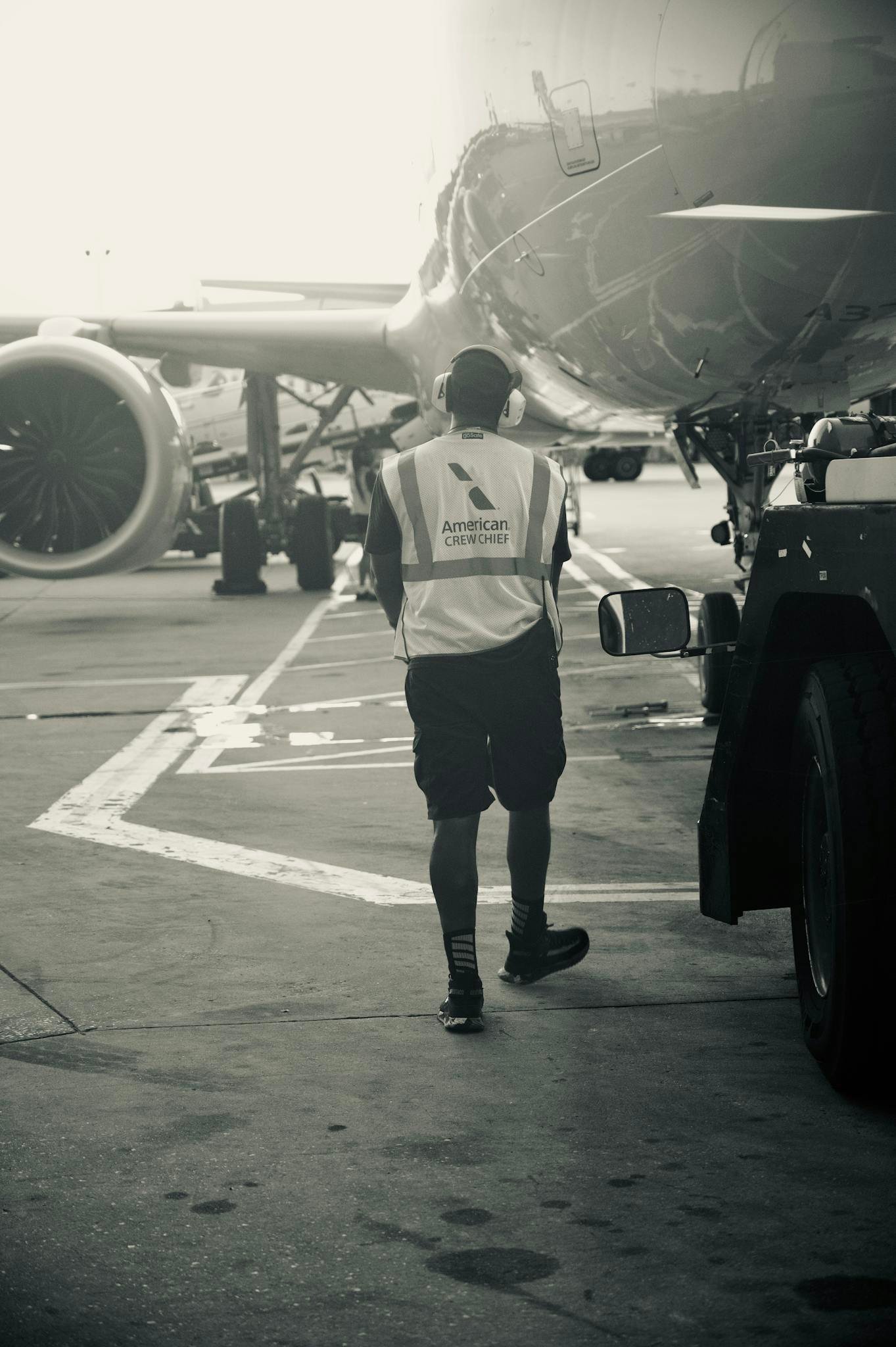 Ground crew member in safety vest walks near airplane at airport terminal